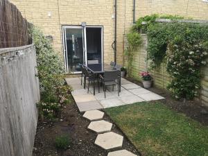 a patio with a table and chairs in a backyard at Green Lake House in Bourton on the Water