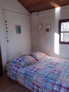 een slaapkamer met een bed met een geruite deken bij El Rancho de Chispero in Isla Patrulla