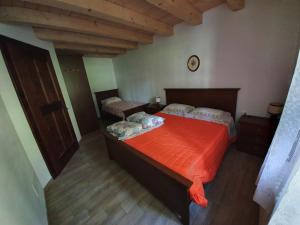 a bedroom with two beds with an orange blanket at Buine Tiere in Cercivento