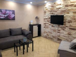 sala de estar con sofá y TV en una pared de piedra. en Apartments Klakor, en Tivat
