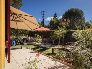 a patio with an umbrella and a table and chairs at Beautiful holiday home near the forest in Carsac-Aillac