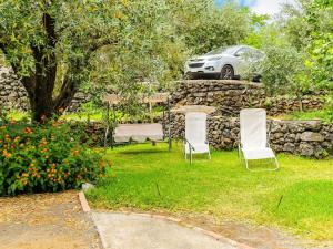 two chairs and a table and a car in a yard at Belvilla by OYO Villa Aloe Charming House in Mascali