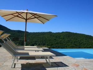 un gruppo di sedie e un ombrellone accanto alla piscina di Apartment in a holiday home in Anghiari with a view of the hills a Galbino