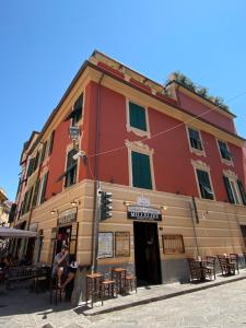 a man sitting in front of a red building at Carruggio 151-2 in Sestri Levante