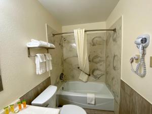 a bathroom with a tub and a toilet and a sink at Roswell Inn in Roswell +26 photos