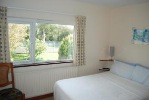 ein Schlafzimmer mit einem Bett und einem großen Fenster in der Unterkunft Dromcloc House in Bantry