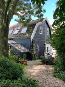a gray house with a garage and a tree at De Vink Bed & Breakfast in Abcoude