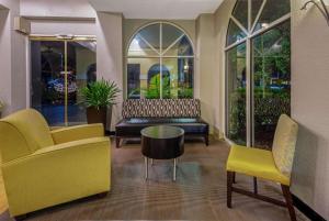 eine Lobby mit gelben Stühlen, einer Bank und einem Tisch in der Unterkunft La Quinta by Wyndham Miami Lakes in Miami Lakes