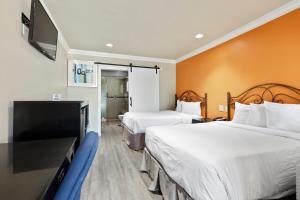 a hotel room with two beds and a flat screen tv at Le Blanc Inn & Suites in El Monte
