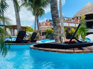 un complejo con piscina con palmeras y tumbonas en Hotel Para Ti - Adults Only en Holbox Island