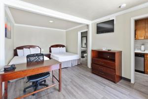Habitación de hotel con escritorio y dormitorio en Le Blanc Inn & Suites en El Monte