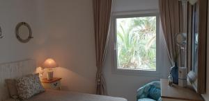 sypialnia z oknem, łóżkiem i krzesłem w obiekcie APARTMENT MARINA CALADOR HARBOURVIEW AIR CONDITION POOL GARDEN TERRASSE PORTO CARI spectacular location w mieście Cala d´Or +37 zdjęć