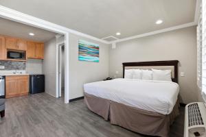 a bedroom with a large bed and a kitchen at Le Blanc Inn & Suites in El Monte