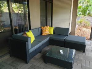 a patio sofa with yellow pillows and a table at Luxury Executive Apartment at Broome Cable Beach in Broome