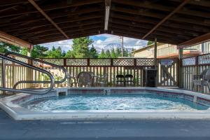 uma banheira de hidromassagem num pátio com cadeiras e mesas em Swiss Holiday Lodge em Mount Shasta