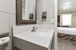 ein Bad mit einem Waschbecken, einem Bett und einem Spiegel in der Unterkunft Le Blanc Inn & Suites in El Monte