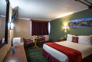 a hotel room with a large bed and a table at Red River Inn Silt - Rifle in Silt