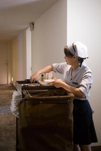 Ambience Hotel Taipei في تايبيه: امرأة تضع شيئا في حقيبة السفر