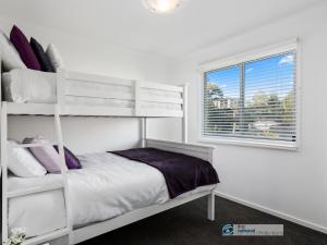 ein Schlafzimmer mit einem weißen Etagenbett und einem Fenster in der Unterkunft 13 Seacombe Grove in Ventnor