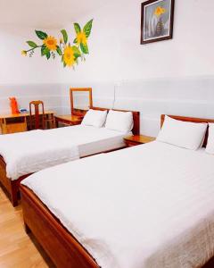 Habitación con 2 camas, sábanas blancas y mesa. en Hoàng Hà Hotel, en Tuy Hoa