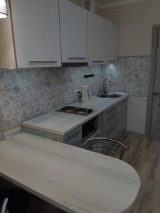 eine Küche mit weißen Schränken, einer Spüle und einem Tisch in der Unterkunft Apartment near stadio Metalist Kharkiv in Kharkov