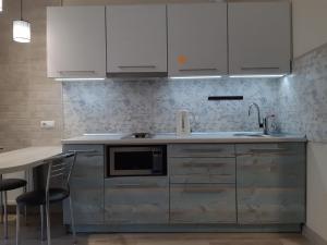 eine Küche mit weißen Schränken und einem Tisch mit Stühlen in der Unterkunft Apartment near stadio Metalist Kharkiv in Kharkov