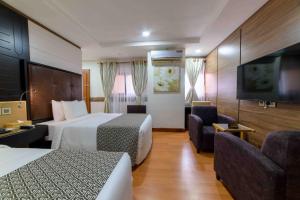 a hotel room with two beds and a flat screen tv at AlphaPlus Apartment 91 in Abuja