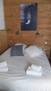 een groot wit bed met 2 kussens en een olifantenfoto bij Alp'azur in L'Alpe-d'Huez