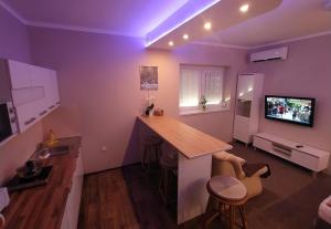 a kitchen with purple lighting and a bar in a room at Emmabella Apartmanok Eger in Eger