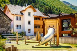 um parque infantil com escorrega em frente a uma casa em B&B Ursi em Andermatt