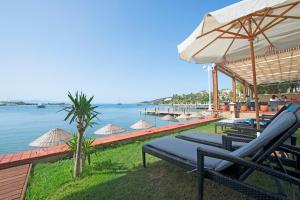 a resort with chairs and umbrellas next to the water at Costa Luvi Hotel Bodrum - All Inclusive in Gümbet