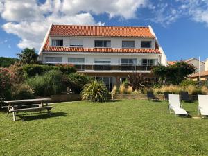 ポルニックにあるHotel Particulier LE ROCHER DES MARAIS "Proximité Plage & Vue mer pour certains hébergements"の芝生の上にピクニックテーブルと椅子がある建物