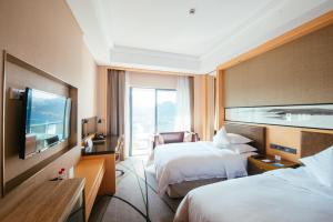 um quarto de hotel com duas camas e uma televisão de ecrã plano em Gloria Resorts Jingdezhen Xishan Lake em Jingdezhen
