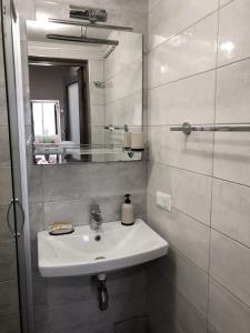 a white bathroom with a sink and a mirror at Apartments Ilona in Odesa