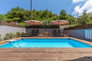 a swimming pool with two umbrellas on a patio at Akalli Studios in Ixia