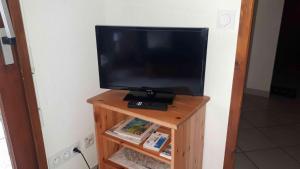 a television on a wooden stand with a remote control at Briançon, Appartement avec jardin et terrasse. in Briançon