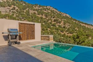 a swimming pool with a grill next to a mountain at Lux View Suites in Kyra Panagia