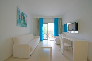 a living room with a couch and a desk and a tv at Costa Luvi Hotel Bodrum - All Inclusive in Gümbet
