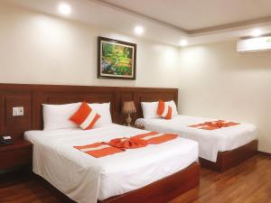 a bedroom with two beds with orange and white sheets at Gia Quý Hotel in Cao Bằng