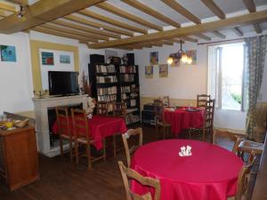 een eetkamer met 2 tafels en een open haard bij Chambres et Tables d'hôtes à l'Auberge Touristique in Meuvaines