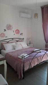 Schlafzimmer mit einem Bett mit rosa Tagesdecke in der Unterkunft B&B La Perla Bianca in Sassari