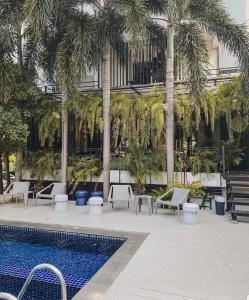 um pátio com palmeiras e uma piscina em Manita Boutique Hotel em South Pattaya
