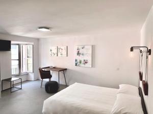 a white bedroom with a bed and a desk at Great2Stay City Center Apartments Locarno in Locarno
