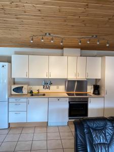 uma cozinha com armários brancos e electrodomésticos brancos em Hafjell Grenda lejligheder em Hafjell