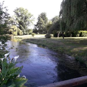 Un río con una valla de madera junto a un parque en LES ENFANTS DU MOULIN, en Saint-Léger-sur-Bresle