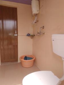 a bathroom with a toilet and a door and a bucket at K.S.N. Varanasi Paying Guest House in Varanasi