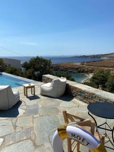 eine Terrasse mit Stühlen, Tischen und einem Pool in der Unterkunft Iris villa in Koundouros