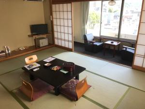 a room with a table and chairs and a living room at Itoen Hotel Bekkan in Ito