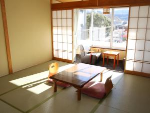 a living room with a table and chairs and a window at Itoen Hotel Bekkan in Ito