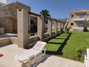 a white bench sitting on a patio next to a yard at Viglia Beach Apartments in Kissamos